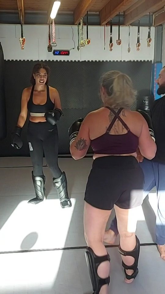 Twee sporters met bokshandschoenen tijdens een training op de mat