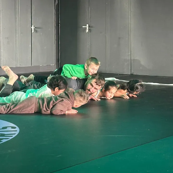 Kinderen spelen samen met hun trainer op de mat tijdens Kids BJJ bij Fight Ready.
